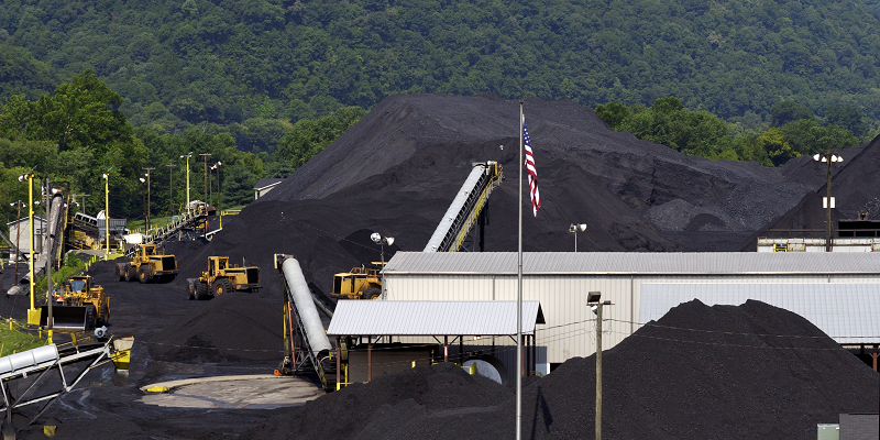 Mounds of coal are piled high awaiting shipment at a coal company terminal in West Virginia. The Appalachian Mountains are in the background.