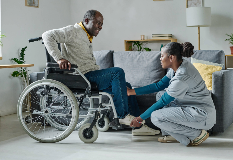 A care worker helps an older person in a wheelchair