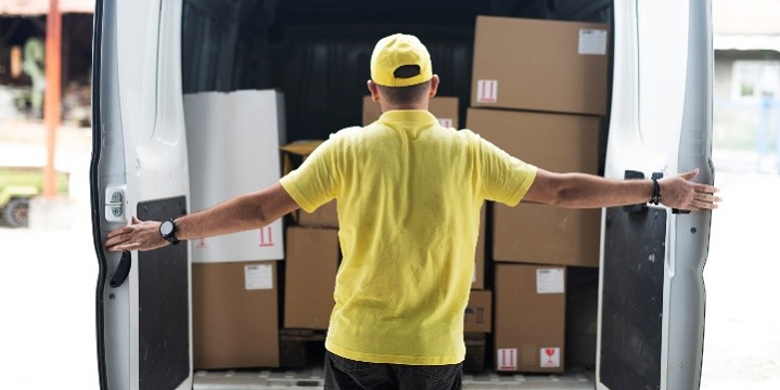 A delivery driver loads boxes into a van