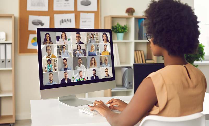 A woman working from home participates in a virtual meeting with her colleagues on her computer