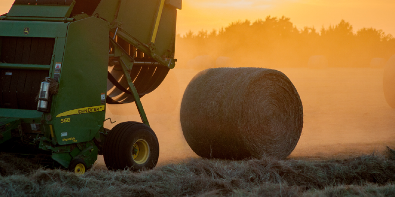 A hay baler with a freshly rolled bale. Photo by Jed Owen on Unsplash