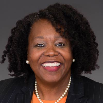 Headshot of Representative Kim Schofield, a smiling Black woman in a bright shirt and blazer, a pearl necklace and earrings.