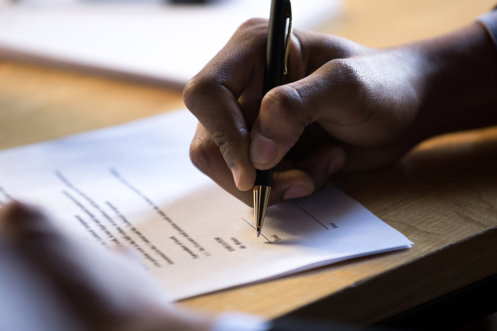 Close-up of a hand signing an employment contract.