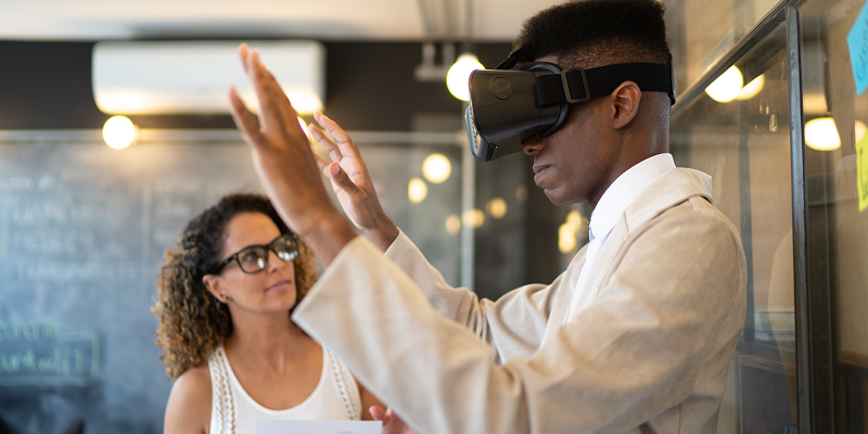 Two coworkers in an office, one is wearing a virtual reality headset