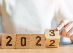 A woman turns over the number block in a row of four blocks to change the year shown from 2022 to 2023