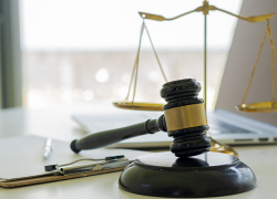 A desk with a laptop, clipboard, a judge's hammer and the scales of justice.