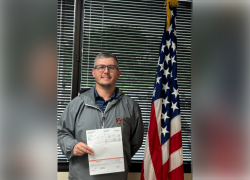 Man posing with a check next to American flag.