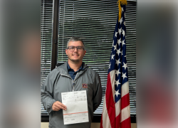 Man posing with a check next to American flag. 