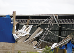 Visible wind damage in the wake of a storm. A roof and siding have been ripped from a building.
