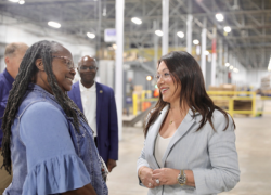 Secretary Lori Chavez-DeRemer speaking with a female worker in a warehouse-type workplace.