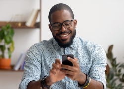 A man smiles while using a smartphone