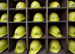 A collection of miners' yellow hard hats on a shelf