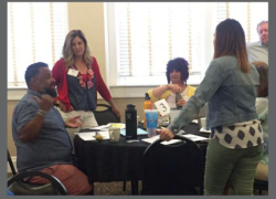 Several people engage in discussion around a table.