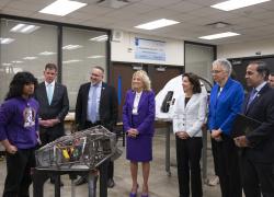 A student displays a rudimentary robot to several adults, including Secretary Walsh and First Lady Jill Biden. 