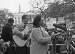 Fannie Lou Hamer singing at the microphones, with a guitarist, during a civil rights demonstration in front of the White House circa 1964. 
