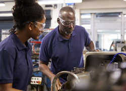A young woman apprentice works in a machine shop with her mentor