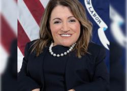 Professional headshot of Julie Hocker in front of the Labor Department flag