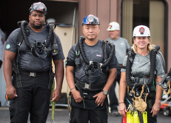 Three diverse members of a mine rescue team wearing hardhats and other safety gear