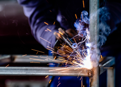 Close-up of a worker welding. The hot metal glows and sparks fly.