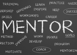 The word MENTOR written on a blackboard, surrounded by related words like coach, training, support, etc.