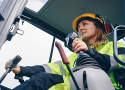 Woman miner in a cab controlling machinery.