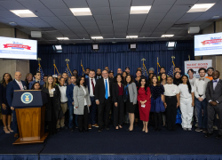 Secretary Su, Secretary Cardona, government officials, students and others crowd together on a stage for a group photo.