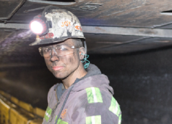 Miner is underground with dust on their face.