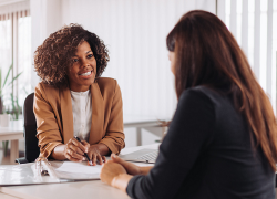 Female financial services salesperson speaking with a client at a bank.
