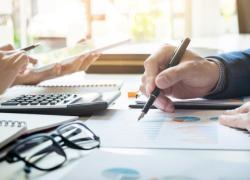 A man and woman sit at an office table, reviewing documents containing data. 