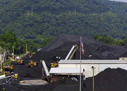 Mounds of coal are piled high awaiting shipment at a coal company terminal in West Virginia. The Appalachian Mountains are in the background.