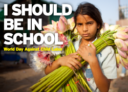 A young girl in India carries cut flowers to sell. The text reads "I should be in school. World Day Against Child Labor."