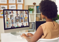 A woman working from home participates in a virtual meeting with her colleagues on her computer