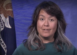 Screen grab of a video shows Wendy Chun-Hoon addressing the camera, seated by a Labor Department flag.