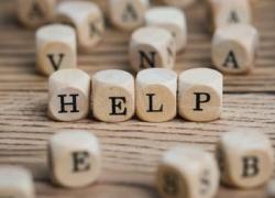 Small alphabet blocks are scattered across a table. In the center, four blocks spell out the word “help.”