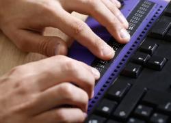 Close-up of hands typing on a braille keyboard