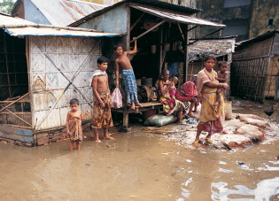 A Bangladeshi family stands outside their home, which is surrounded by floodwaters.