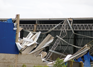 Visible wind damage in the wake of a storm. A roof and siding have been ripped from a building. 