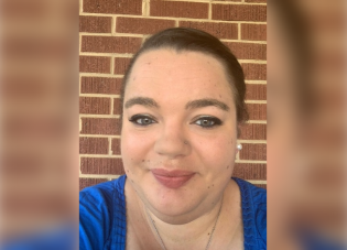 Headshot of Melyssa Scott, smiling in front of a brick wall