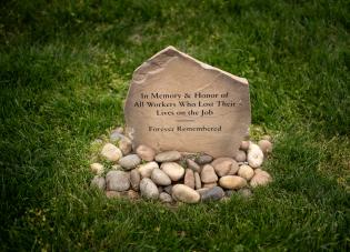 A memorial stone with an engraving that reads, “In memory and honor of all workers who lost their lives on the job.”