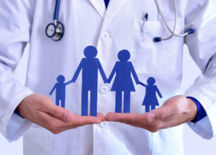 Blue, paper cut out of family in the hands of a medical professional.