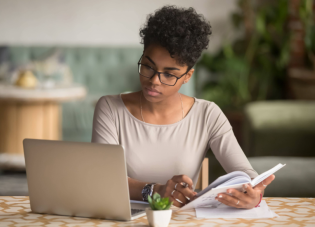 A young woman looks at her computer while evaluating her finances.