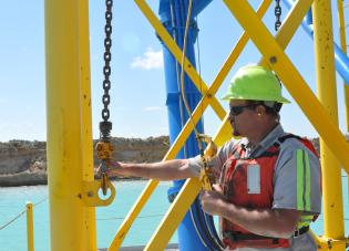 A miner stands on equipment at a surface mine.