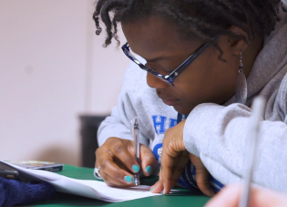 Close-up of an educator filling out paperwork at a desk during a training session.