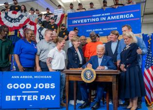 President Joe Biden, flanked by union members and labor leaders, signs an Executive Order to promote good jobs. Signs around him say "Investing in America" and "Good jobs, better pay." (Official White House Photo by Adam Schultz) 