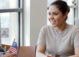 A female service member meets with a civilian woman in an office.