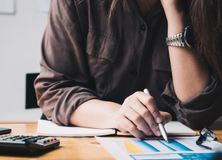 A woman sitting at a desk reviews a financial report
