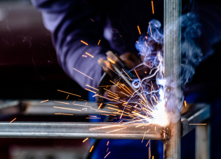 Close-up of a worker welding. The hot metal glows and sparks fly. 