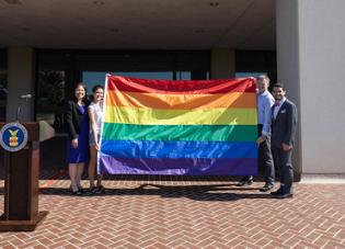 Deputy Secretary Julie Su standing with three individuals holding the PRIDE Flag. 