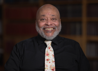 Close-up of Rob Robinson, a Black man wearing a dark shirt and a tie that has a flower pattern.