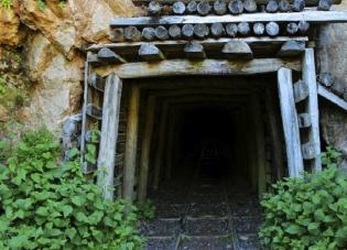 An entrance to an abandoned mine in the side of a rock formation. The tunnel leads to an underground coal mine.